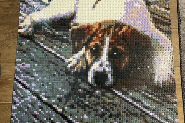 A finished brick mosaic of a resting dog, laid flat on a wooden table